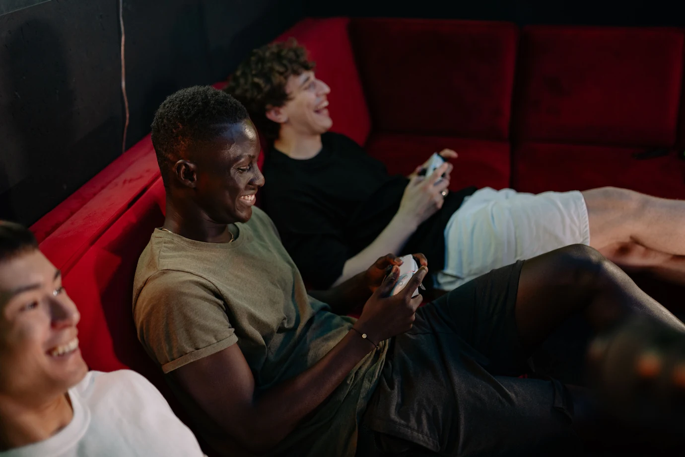 Three friends laughing while playing a couch co-op game at night